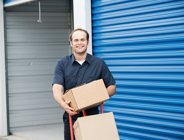 Smiling worker moving cardboard boxes