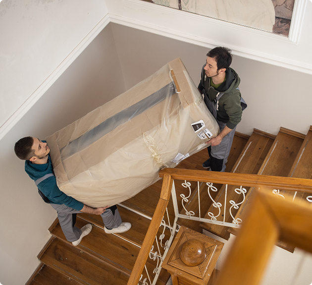 Workers lifting mattress on staircase
